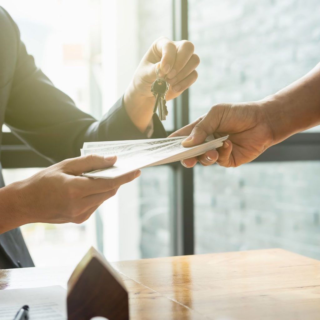Hands exchanging house keys and cash during a property transaction