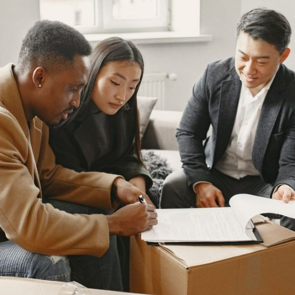 Couple signing documents with a real estate agent.
