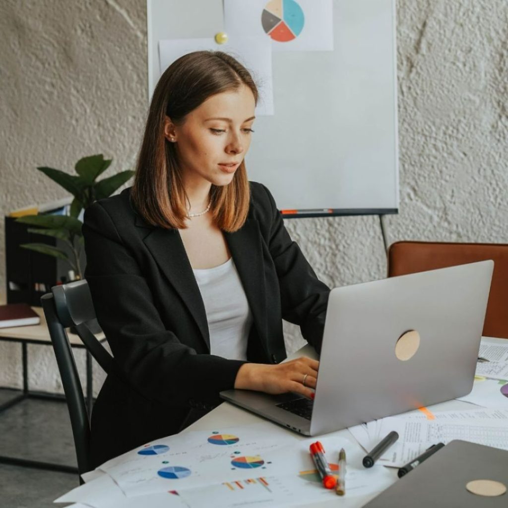 Businesswoman working on a laptop with charts and graphs on the desk