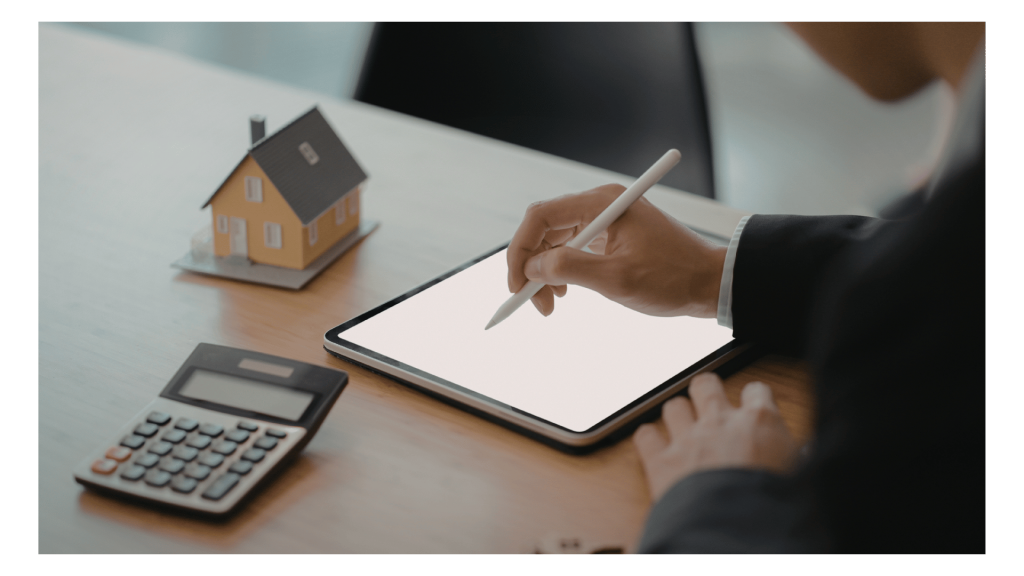 Seller using a digital tablet to get MLS access next to a calculator and miniature model house.