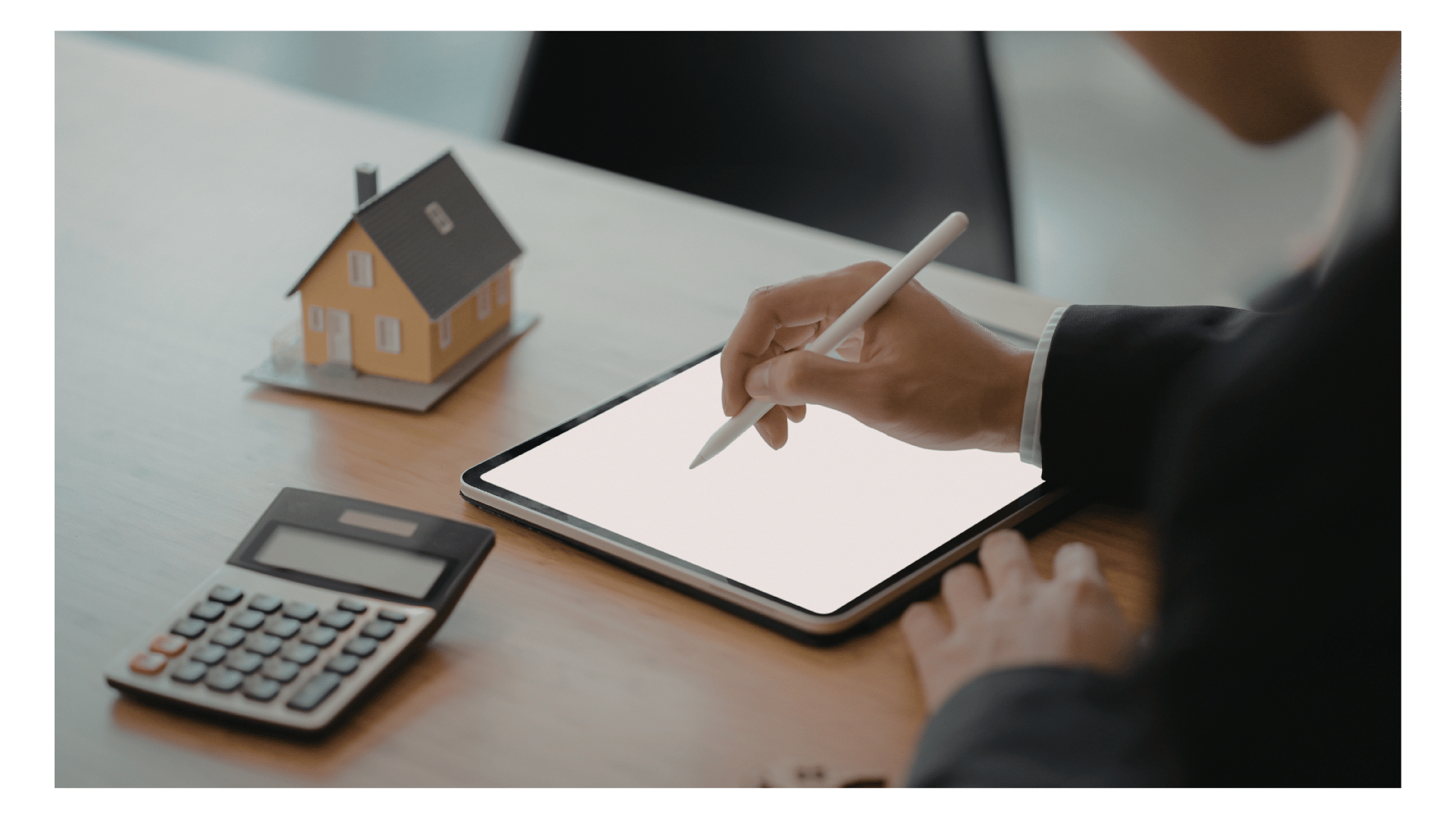 Seller using a digital tablet to get MLS access next to a calculator and miniature model house.