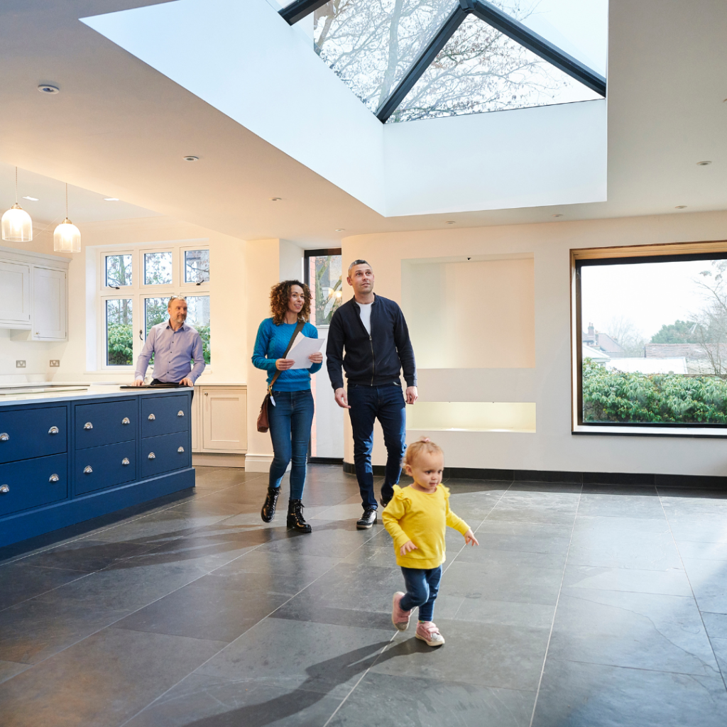 Young family touring a modern home with a real estate agent.