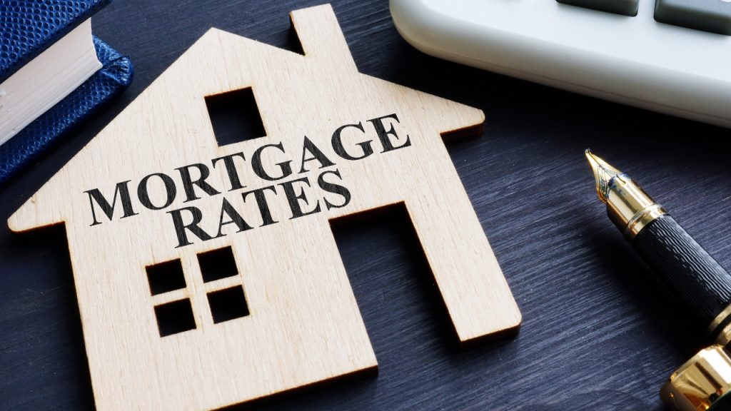 Wooden house cutout with the words 'Mortgage Rates' next to a pen.