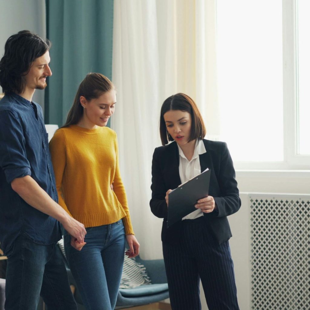 Real estate agent showing documents to a couple during a home tour.
