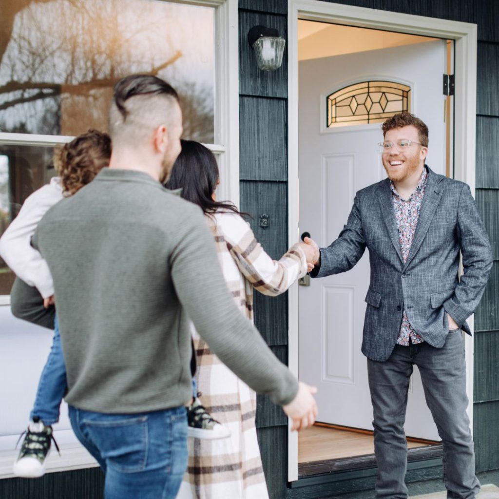Homeowner greeting a couple with a child at the front door.