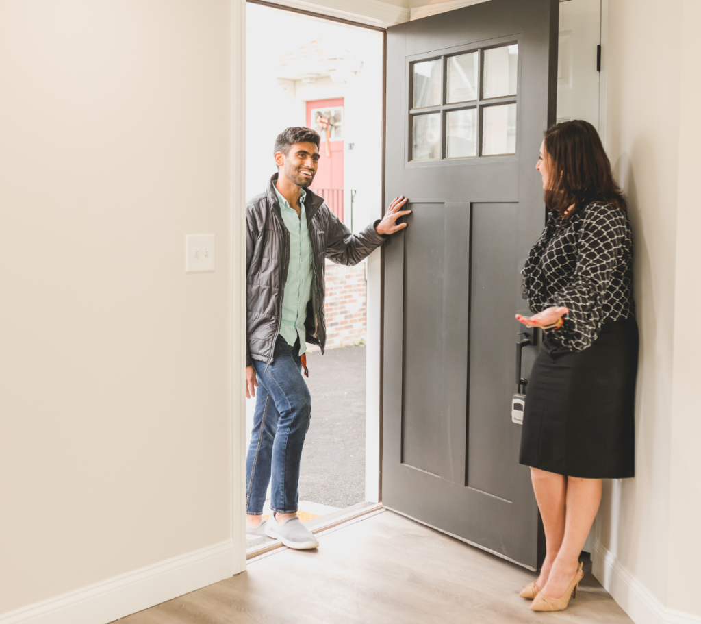 A man entering a home for a showing, greeted by a woman near the door.