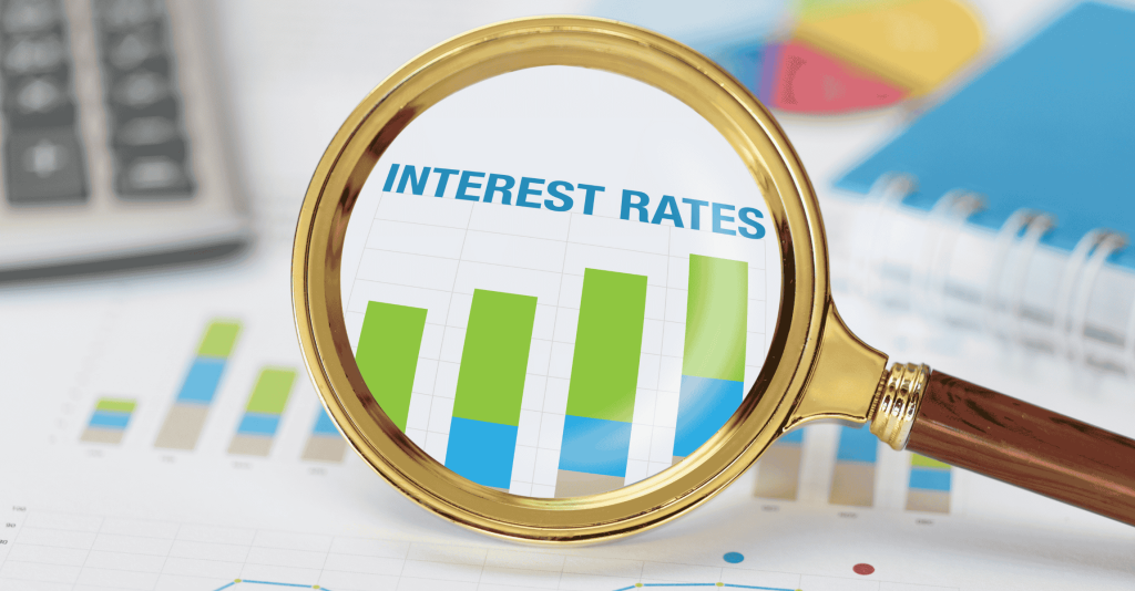 Magnifying glass focusing on rising interest rates chart.