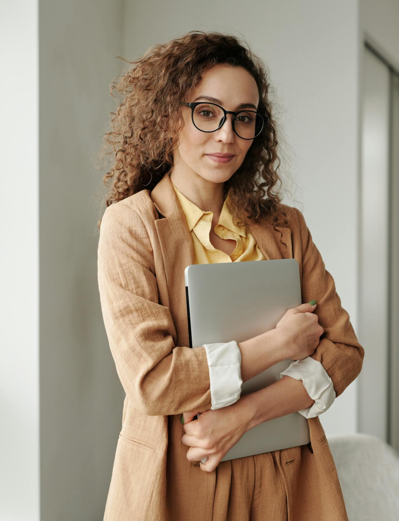 Woman wearing glasses holding a laptop.
