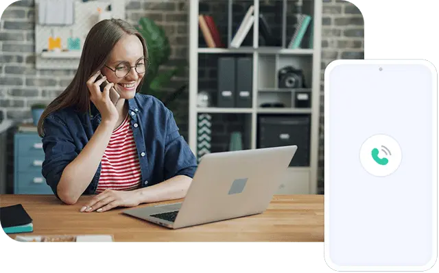 A female on her phone smiling while looking at the laptop screen.