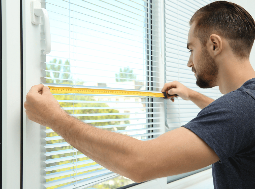 man inspecting window with tape measure in house