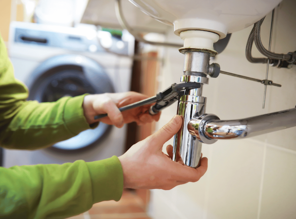 man fixing water pipe in bathroom